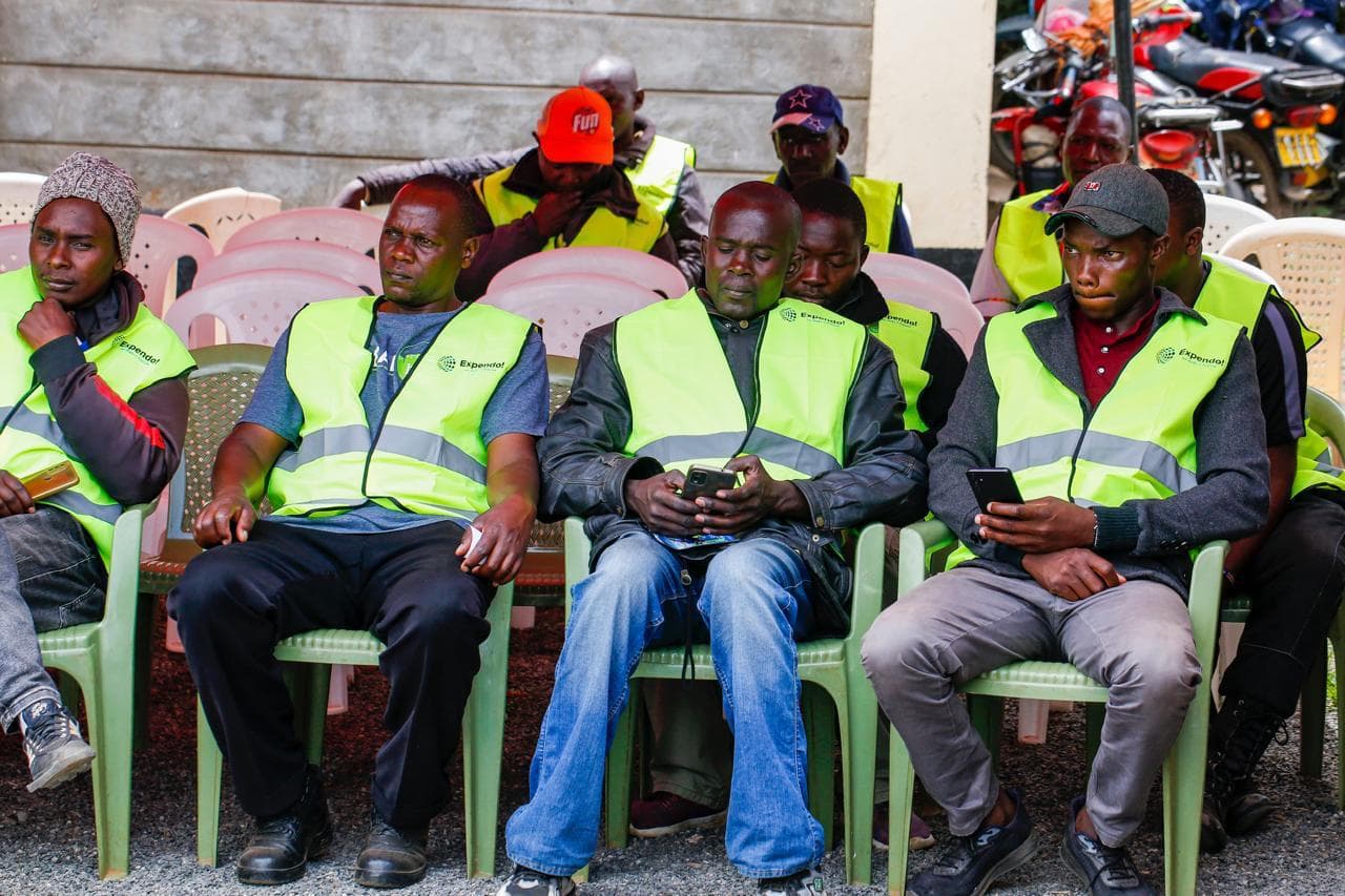 Expendo riders seated and checking phones at an event